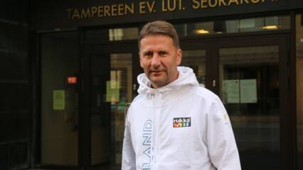 Tuomiorovasti Olli-Pekka Silfverhuth seisoo Tampereen seurakuntien rakennuksen edustalla. Hän on pukeutunut Suomen paralympiajoukkueen edustusasuun.