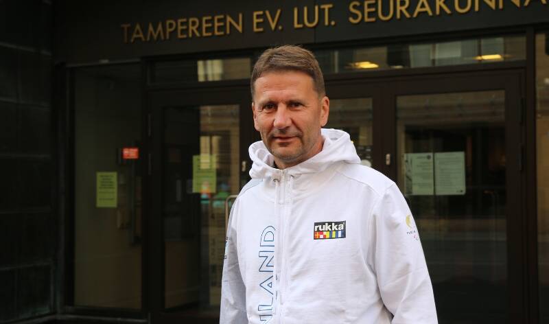 Tuomiorovasti Olli-Pekka Silfverhuth seisoo Tampereen seurakuntien rakennuksen edustalla. Hän on pukeutunut Suomen paralympiajoukkueen edustusasuun.
