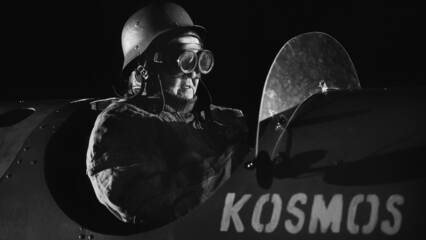 Lentäjähahmo lasit silmillä, raketin kyljessä lukee sana Kosmos.