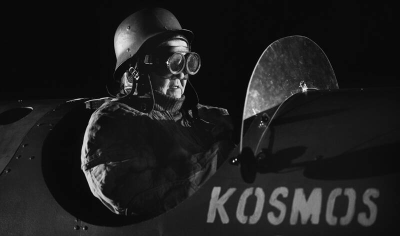 Lentäjähahmo lasit silmillä, raketin kyljessä lukee sana Kosmos.