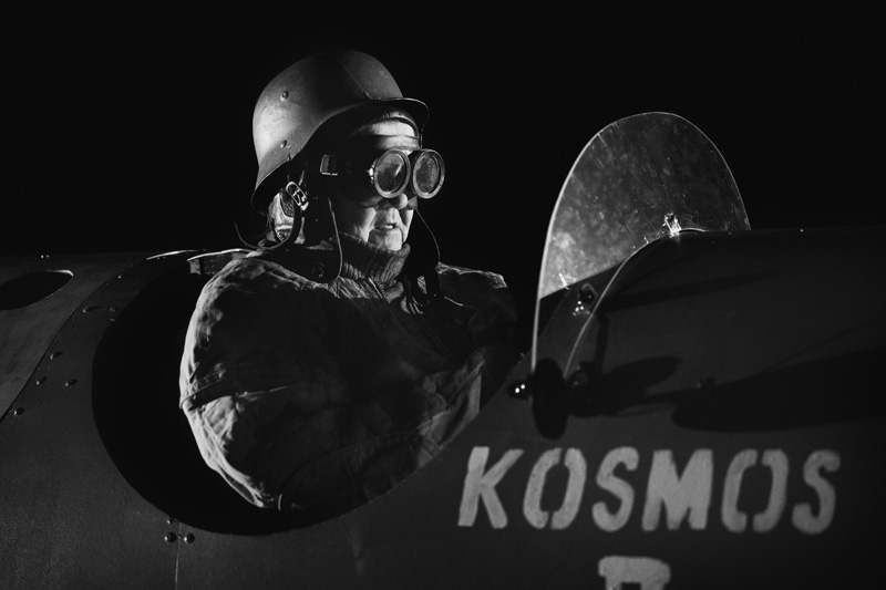 Lentäjähahmo lasit silmillä, raketin kyljessä lukee sana Kosmos.