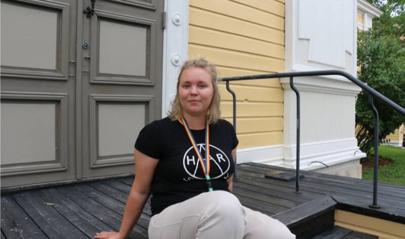 Nainen istuu kirkon portailla.