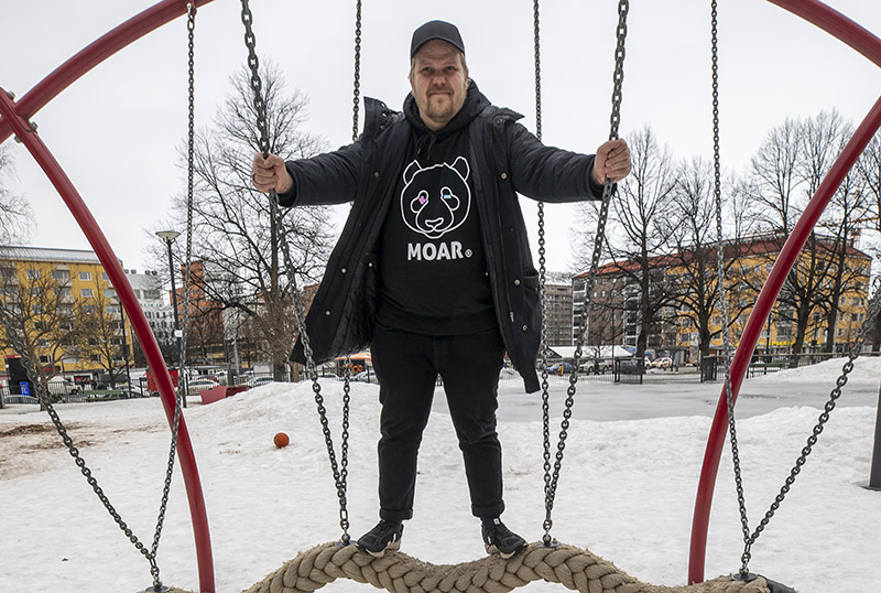 Lippalakkipäinen mies seisontakeinussa.
