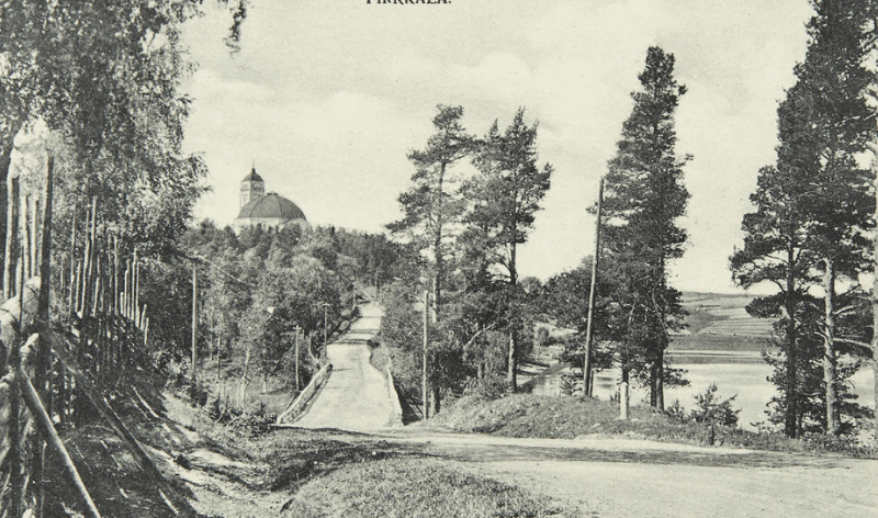 Vanha kuva, jossa näkyy tietä, metsää ja horisontissa kirkko.
