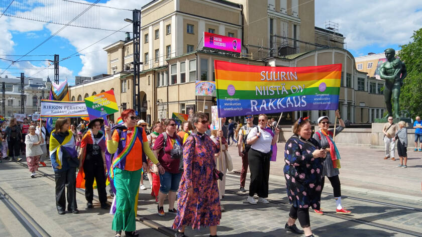 Pride-marssijoita Hämeenkadulla. Banderollissa lukee "Suurin kaikista on rakkaus, Tampereen seurakuntien sateenkaarityö".