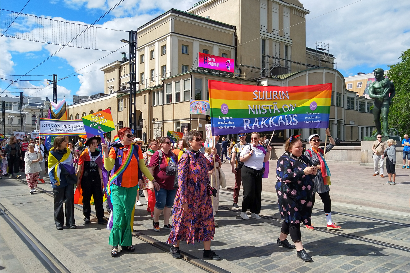 Pride-marssijoita Hämeenkadulla. Banderollissa lukee "Suurin kaikista on rakkaus, Tampereen seurakuntien sateenkaarityö".