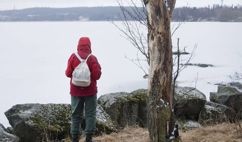 Nainen katselee kevättalvista järvimaisemaa.