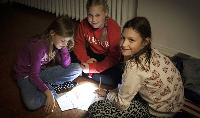Kolme tyttöä miettii rastikilpailun vastauksia Yö kirkossa -tapahtumassa.