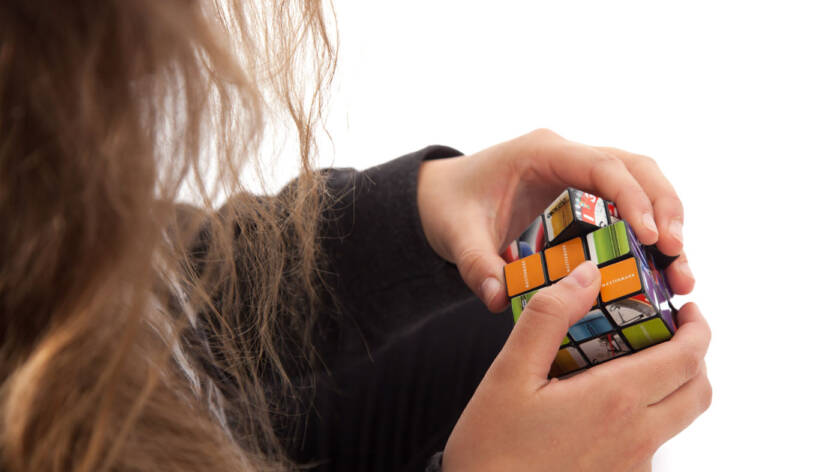 Nuorihenkilö pyörittää käsissään rubikin kuutiota.