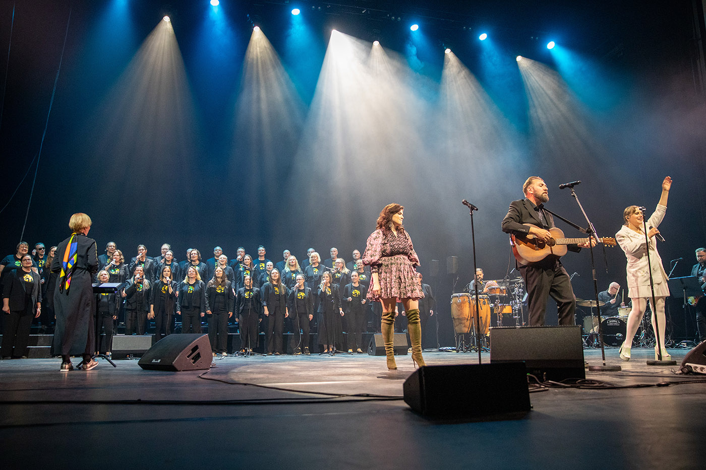Mystisen tumma lava, jossa taustalla gospelkuoro ja etualalla kolme artistia eli Suvi Teräsniska, Knipi ja Yona
