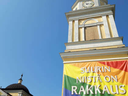 Tampereen Vanhan kirkon kellotapulissa banderolli sateenkaaren väreissä. Banderollissa lukee teksti: Suurin niistä on rakkaus.