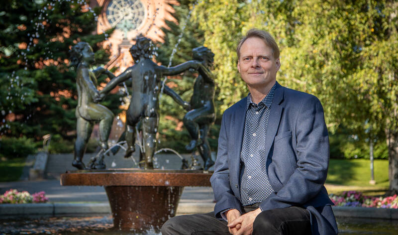 Yhtymäjohtaja Tapani Rantala istuu Aleksanterin kirkon puistossa Kevät-suihkulähteen edustalla.