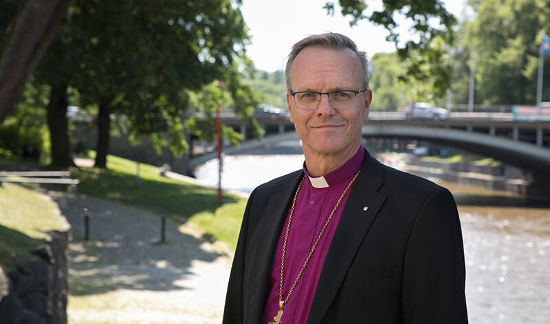 Arkkipiispa Tapio Luoma hymyilee kameralle ulkona kesäisellä ilmalla.