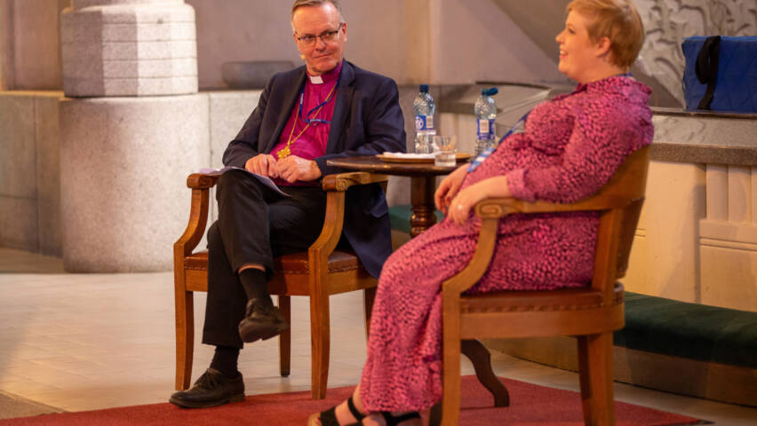 Tapio Luoma ja Annika Saarikko istumassa tuoleilla Tampereen tuomiokirkon alttarin edessä.