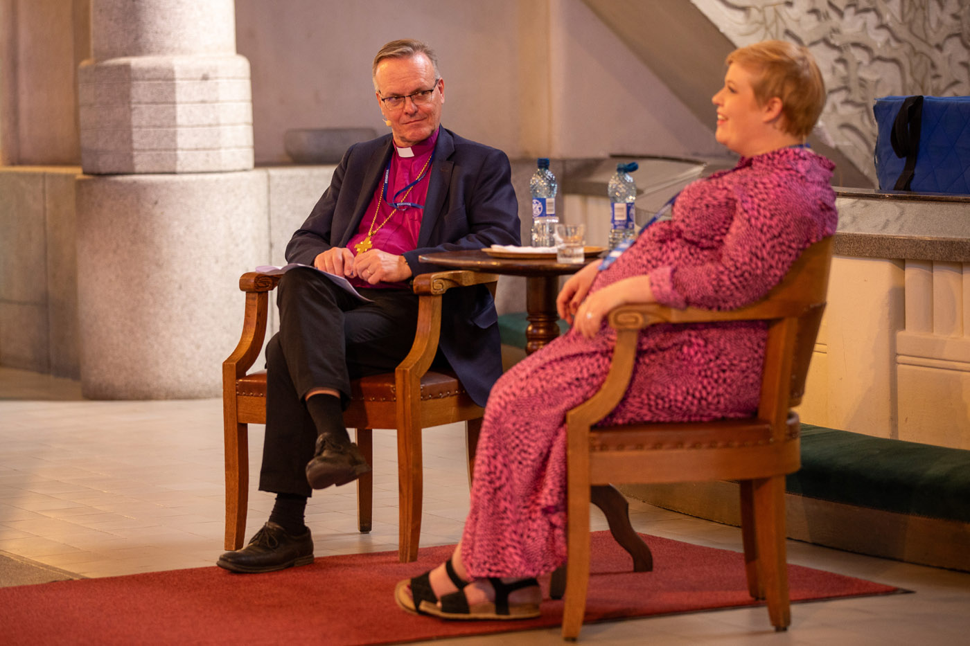 Tapio Luoma ja Annika Saarikko istumassa tuoleilla Tampereen tuomiokirkon alttarin edessä.