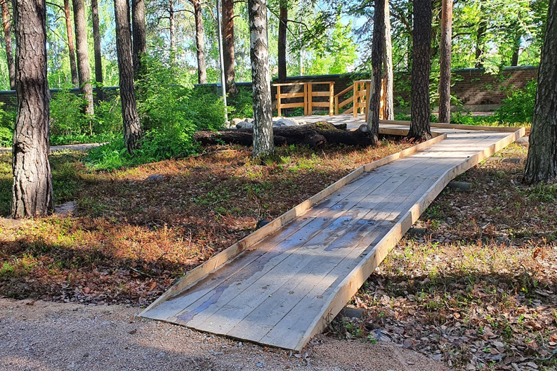 Esteetön reitti tuhkiensirottelualueelle mäntyjen keskellä.