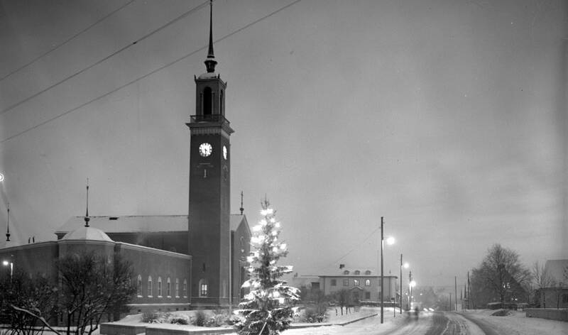 Mustavalkoin valokuva lumisesta kirkosta ja sen ympäristöstä.