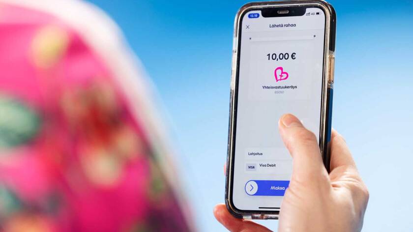 Kädessä olevassa kännykän näytössä näkyy 10 € ja Yhteisvastuu keräyksen sydänlogo.