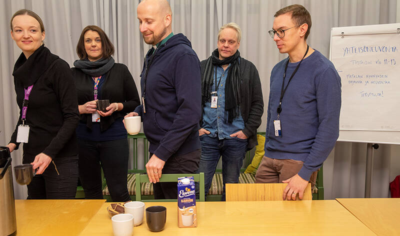 Viisi ihmistä mukit käsissä menossa vasemmalle.
