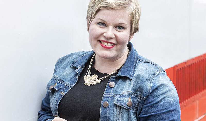 Lyhythiuksinen hymyilevä nainen, jolla on meikkiä.