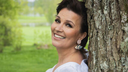 Laulaja Arja Koriseva nojaamassa puuhun.