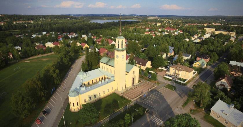 Aerial view of Viinikka Church and the surrounding neighbourhood in summer. The church’s pale tower rises above trees and residential buildings.