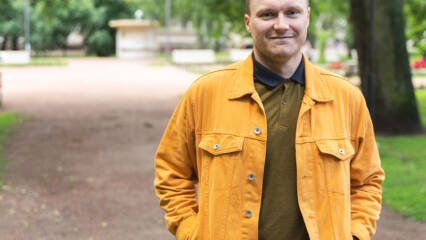 Ylävartalokuva hymyilevästä miehestä vihreässä luonnossa.