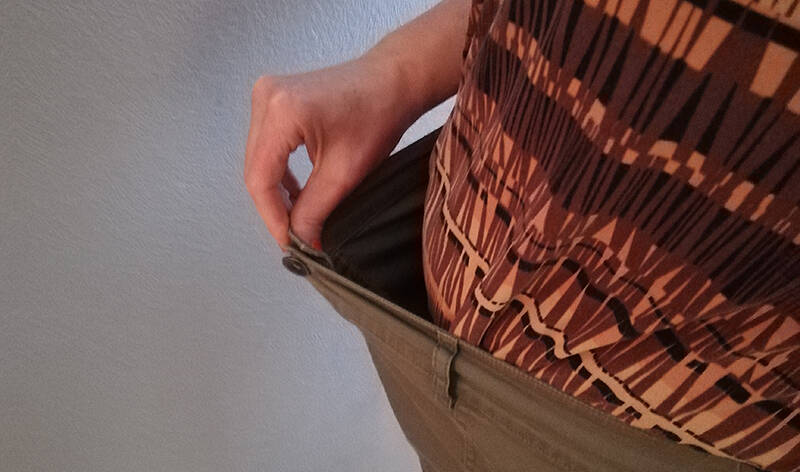 Hoikistunut vyötärö. Käsi pitelee ylisuuria housuja ylhäällä.
