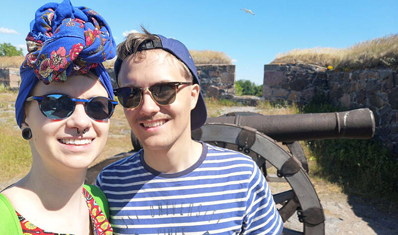 Kihlatut hymyilevät turistikohteessa, tausta vanha tykki.