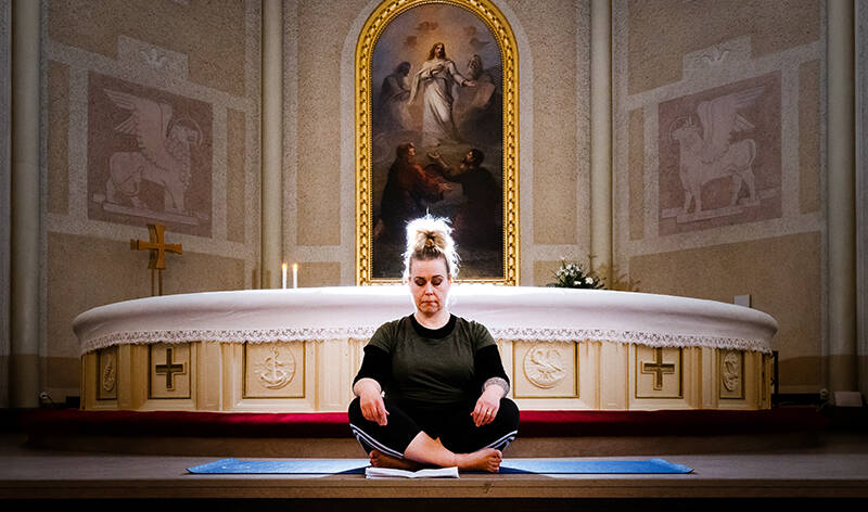 Pastori Mirella Lehtola joogaa Aleksanterin kirkon alttarin edessä.