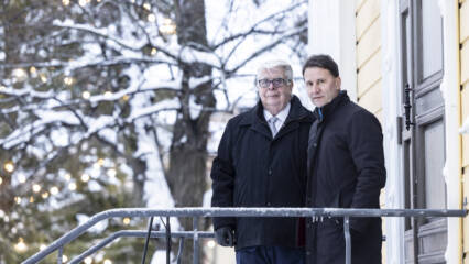 Kalervo Kummola ja Olli-Pekka Silfverhuth Vanhan kirkon portailla, taustalla luminen valaistu puu.
