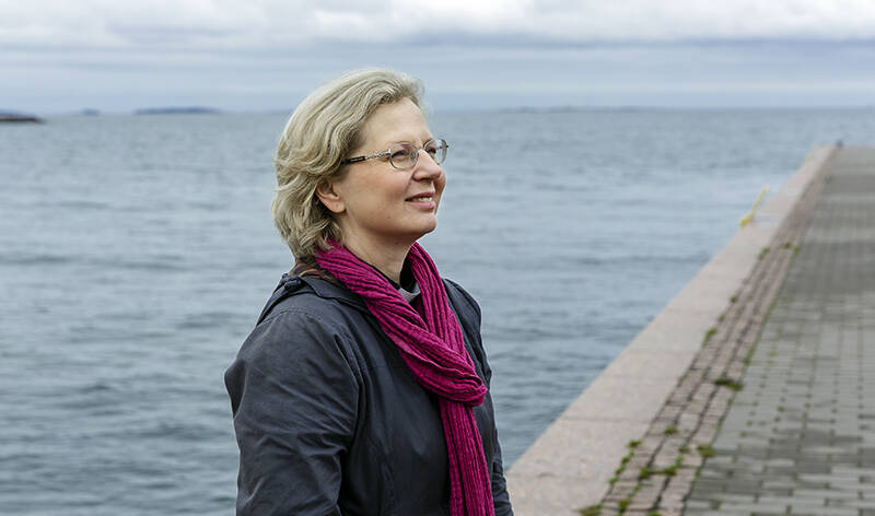 Sivuprofiili-puolivartalokuva naisesta veden äärellä.