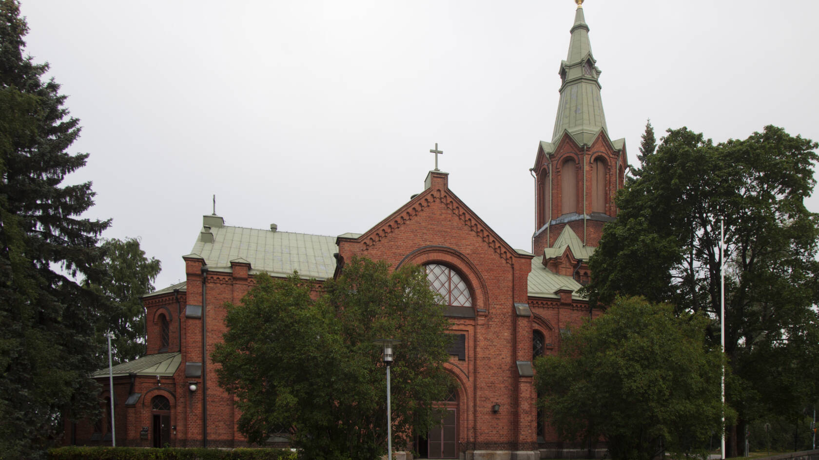 Messukylän kirkko näkyy hautausmaan takaa. Kirkko on punatiilestä rakennettu uusgoottilainen kirkko.