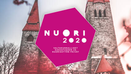 NUORI2020 -päivien kuusikulmainen logo leijuu tunnelmallisen Tampereen tuomiokirkon edessä. Kuva on sävyltään viileän punainen.