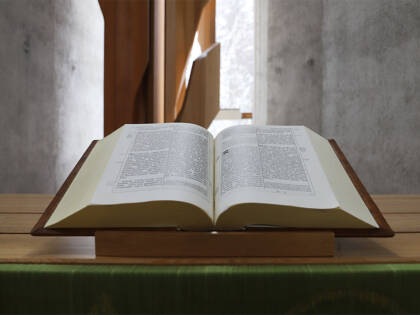 A bible on the table with light coming from a window behind it.