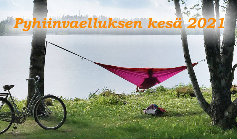 Järven rannalla koivuihin kiinnitetyissä punaisessa riippumatossa istuu ihminen katsellen usvaiselle järvellle, maton vasemmalla puolella polkupyörä, teksti Pyhiinvaelluksen kesä 2021.