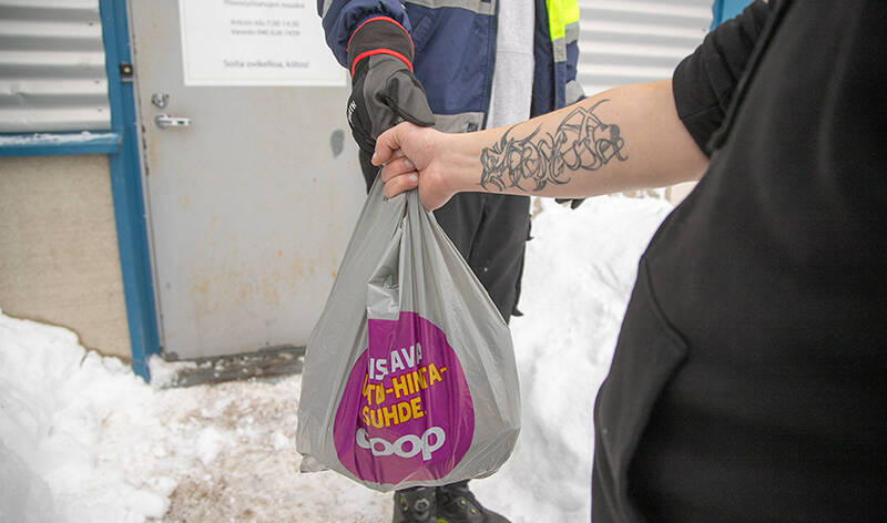 Ihminen tarttuu hänelle ojennettuun ruokakassiin Nekalan ruokapankin pihassa.