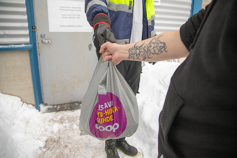 Ihminen tarttuu hänelle ojennettuun ruokakassiin Nekalan ruokapankin pihassa.