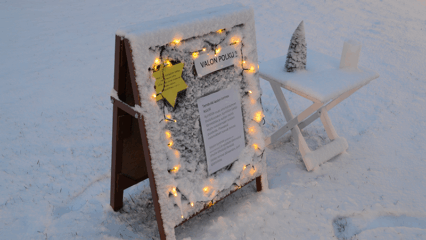 Luminen ilmoitus ständi, johon on laitettu jouluvalot kiinni.
