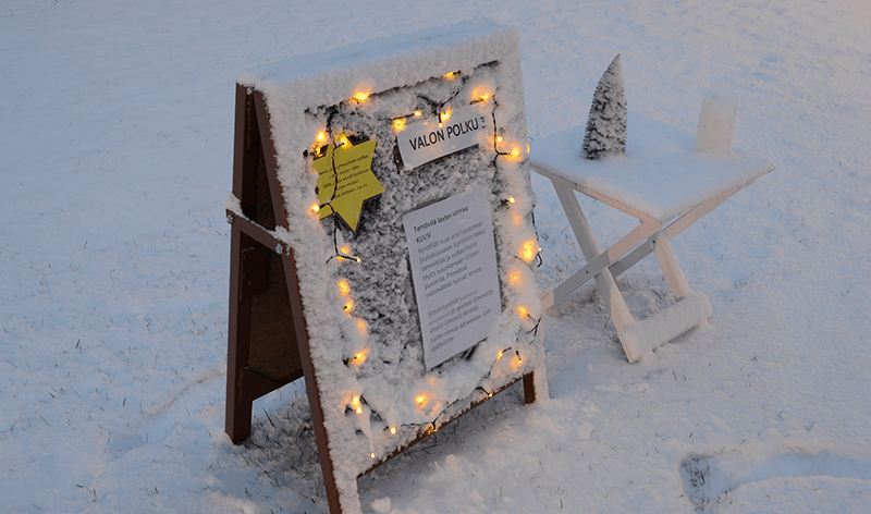 Luminen ilmoitus ständi, johon on laitettu jouluvalot kiinni.