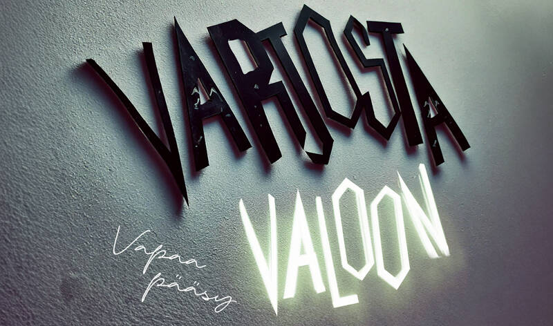 Tyylitelty teksti seinällä, jossa lukee ”Varjosta valoon”. Sana ”valoon” hohtaa kirkkaasti ja ”varjosta” on musta ja luo varjovaikutelman.