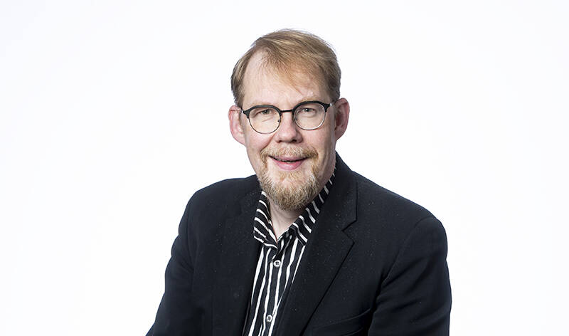 Hymyilevä mies valkoisella taustalla.