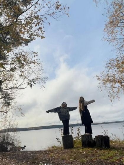 kaksi nuorta seisoo järven rannassa pölkyillä kädet levällään. On syksy.