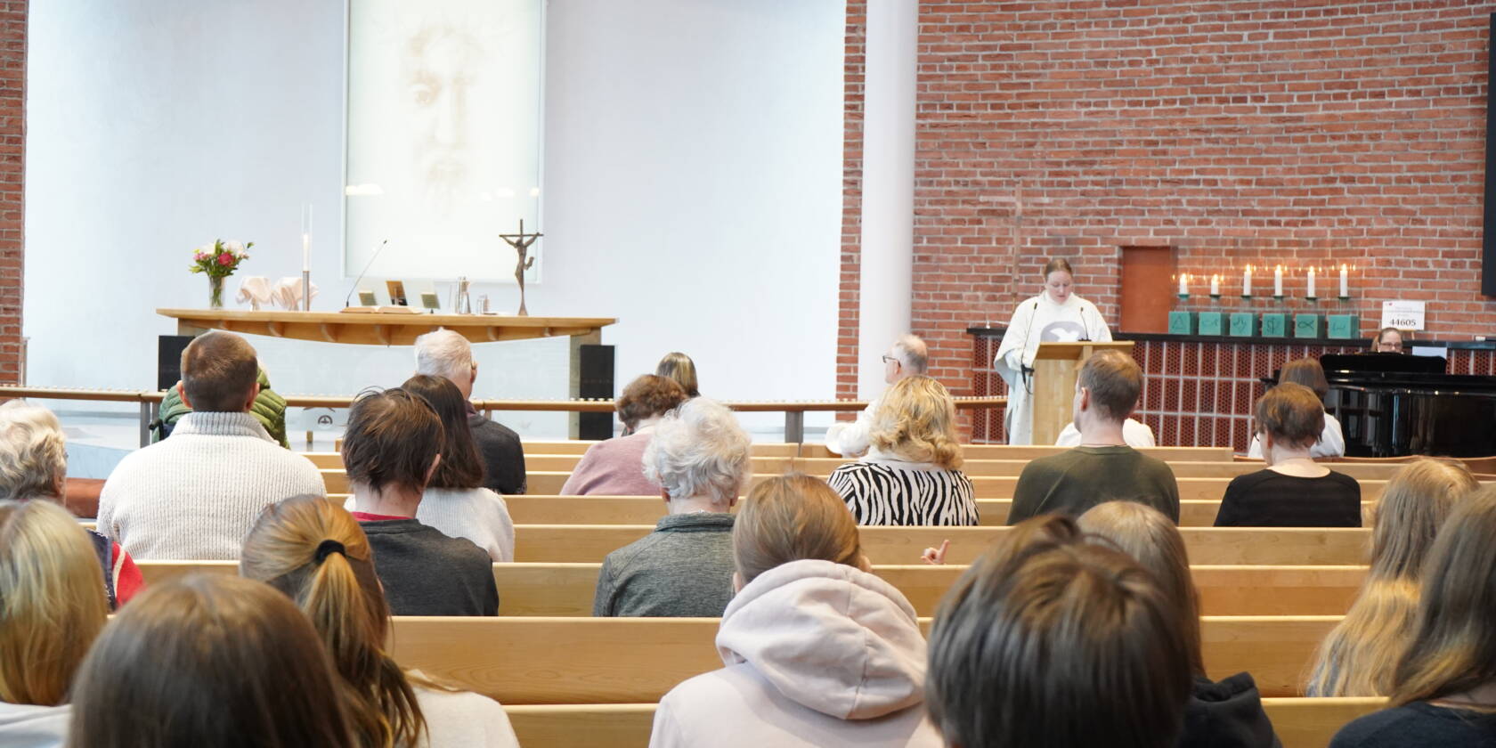 IHmisiä Atilahden kirkkosalissa istumassa. kuva otettu salin takaa. Pappi lukupuletissa puhumassa.