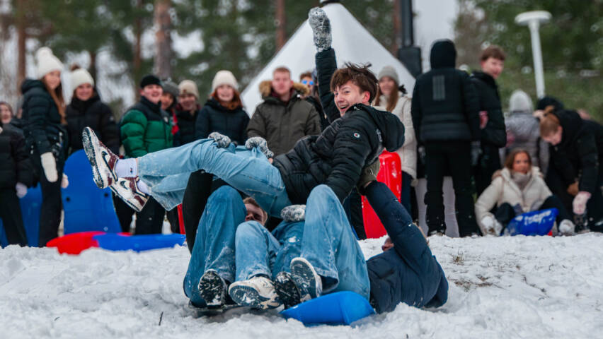 Pulkkamäessä pulkkailijat kannattelevat päänsä yläpuolella henkilöä