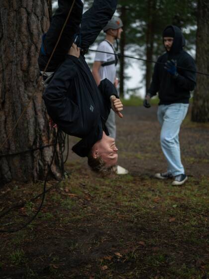 Henkilö roikkuu pää alaspäin kiipeilyköyden varassa