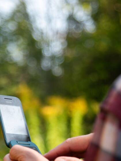 A person holding a phone outdoors.