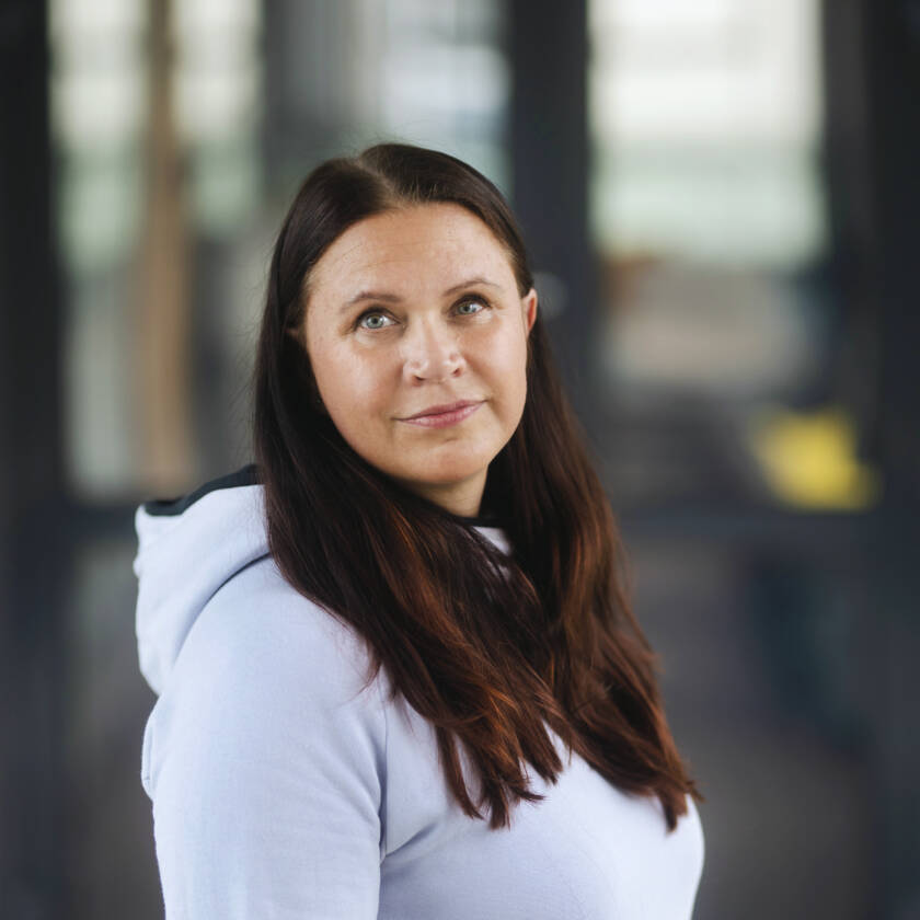 Nainen, jolla on tummat pitkät hiukset seisoo vinoittain kameraan.