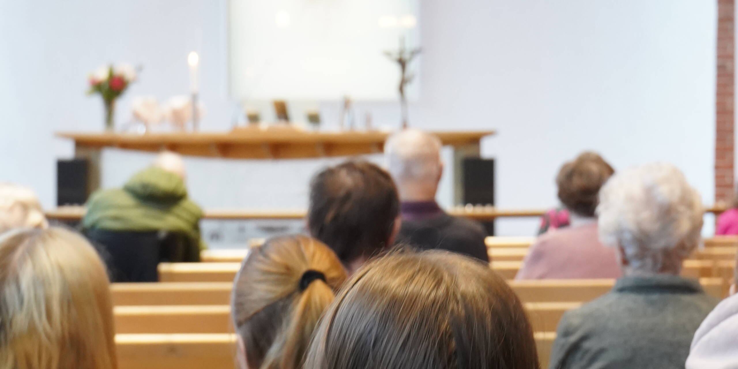 Messuväkeä istumassa Aitolahden kirkkosalissa. Kuva otettu takaapäin