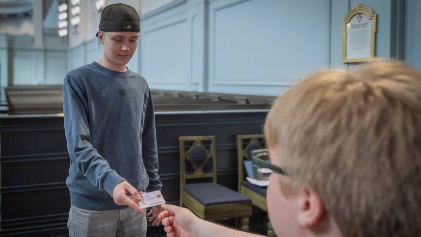 Mies ojentaa henkilötodistusta vaalitoimitsijalle.
